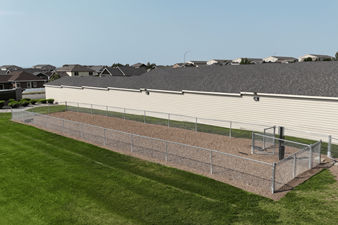A large white building with a grey roof and a chain link fence in front of it.