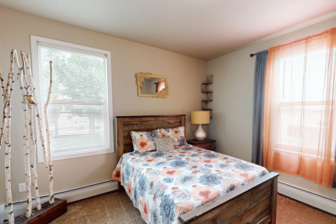 A bedroom with a bed, a lamp, and a mirror on the wall.