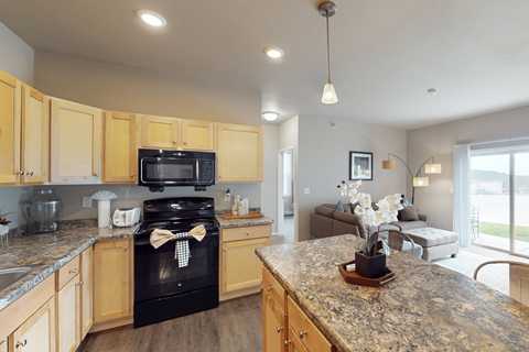 A kitchen with a black oven and wooden cabinets.