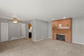 a living room with a brick fireplace and a ceiling fan