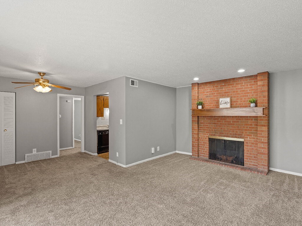 the living room of an apartment with a brick fireplace