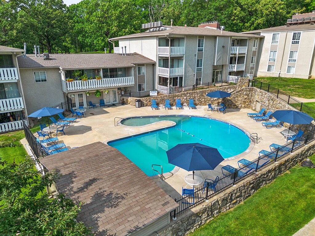 a large swimming pool with umbrellas in front of apartment building