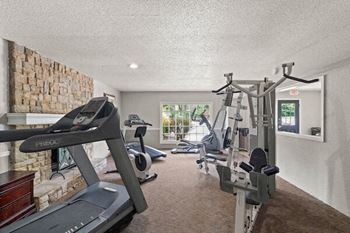 the gym has plenty of equipment and a stone wall
