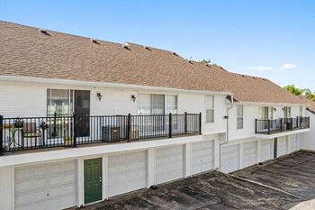 a white house with a balcony and white garage doors