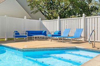 a swimming pool with blue lounge chairs next to it