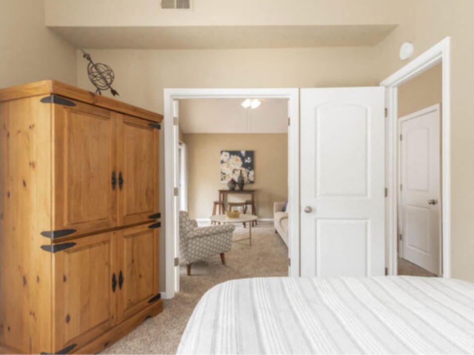 a bedroom with a bed and a dresser and a living room