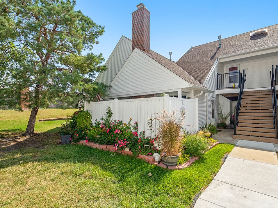 the front yard of a house with a white fence and flowers