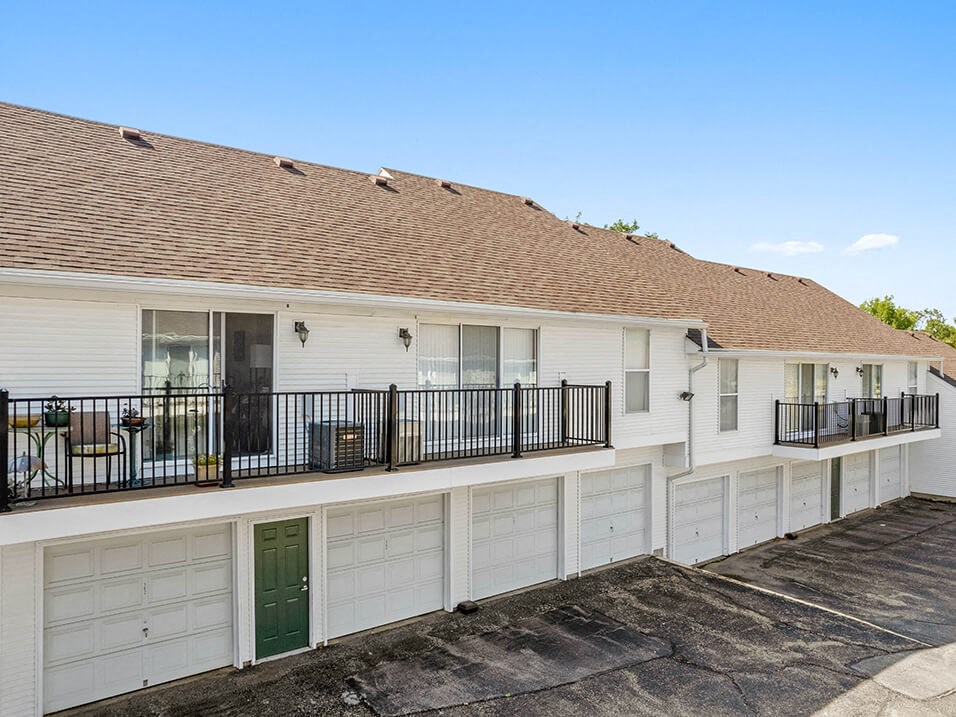 the front of a white house with a green garage door