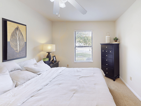 A bedroom with a large bed, a nightstand with a lamp, and a painting on the wall.