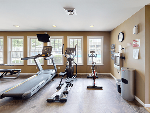 A spacious gym with a treadmill, elliptical trainer, and stationary bike.