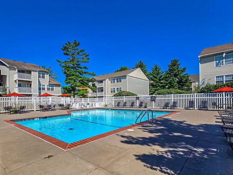 A swimming pool surrounded by a white fence and apartment buildings.