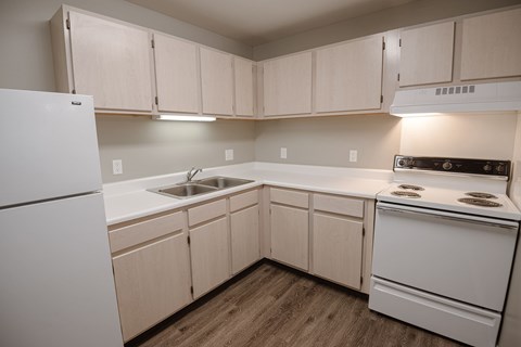 A kitchen with white appliances and wooden cabinets.