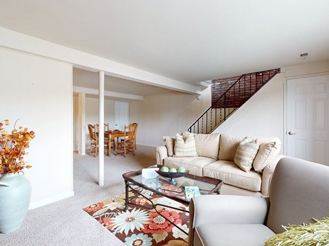 A living room with a couch, coffee table, and a staircase.