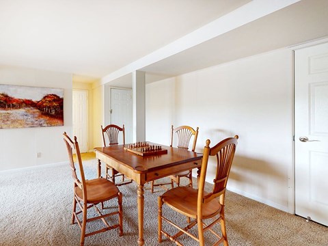 A wooden table with chairs in a room with a painting on the wall.