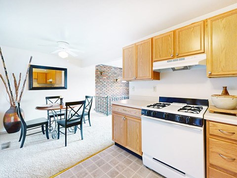 A kitchen with a white stove and wooden cabinets.