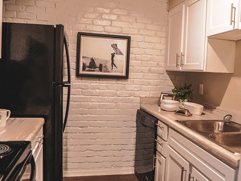 a kitchen with white cabinets and a black refrigerator