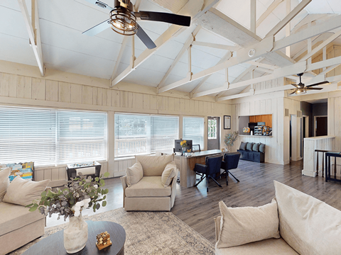 A living room with a ceiling fan and a table with a vase of flowers on it.