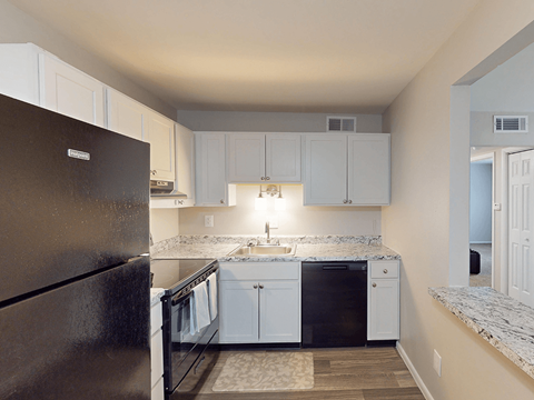 A kitchen with a black refrigerator and white cabinets.