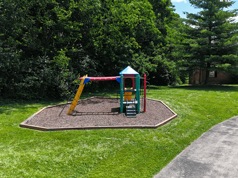 A playground with a yellow slide and a green and red playhouse.