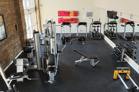 A gym with a variety of equipment including weights and weight machines.