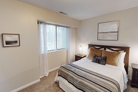 A bedroom with a large bed and a window with curtains.