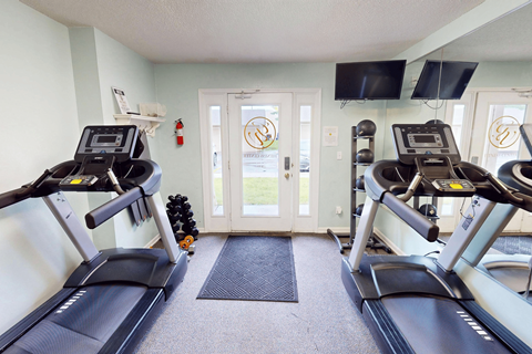 A gym with treadmills and a fire extinguisher on the wall.