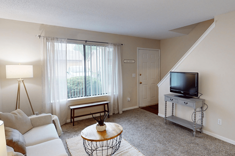 A living room with a white couch, a coffee table, and a television.