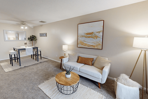 A living room with a white couch, a coffee table, and a painting on the wall.