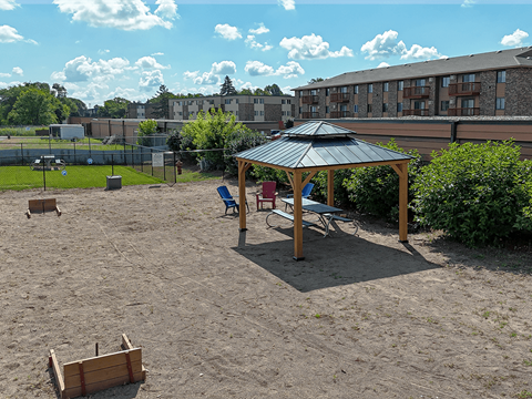 A sandy playground area with a wooden structure and a black umbrella.