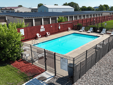 A pool surrounded by a black fence with a sign on it.