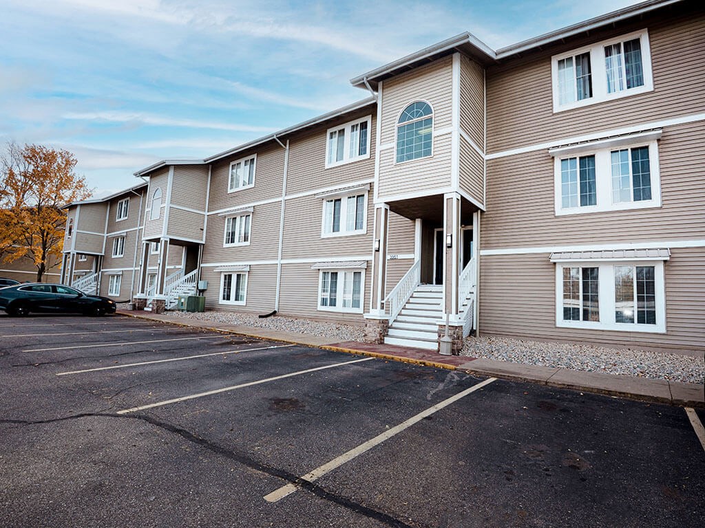 A parking lot in front of a two-story apartment building.