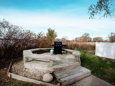 A picnic table with a grill and a trash can on it.