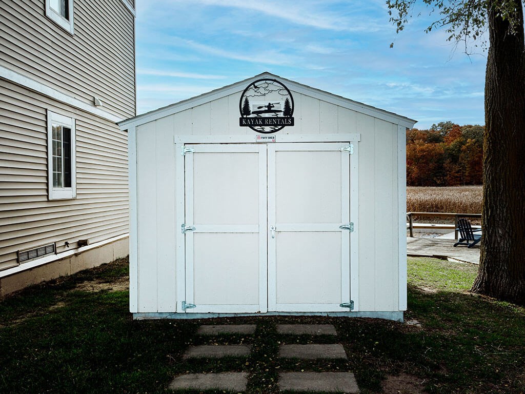 A white shed with a black logo on the top.