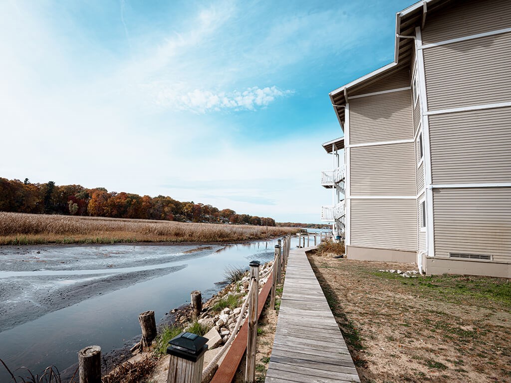 A wooden walkway runs alongside a body of water with a building on the right.