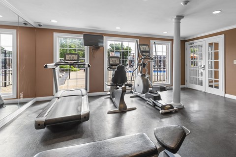 A gym with treadmills, elliptical machines, and a weight bench.