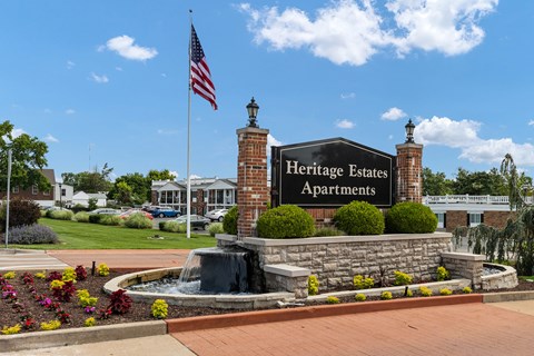 A sign for Heritage Estates Apartments is in front of a brick building.