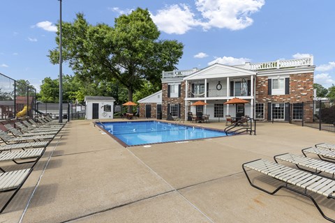 A pool area with sun loungers and a building in the background.