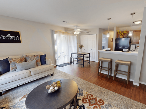 A living room with a white couch and a coffee table with a bowl of fruit on it.