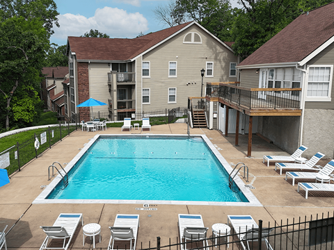 A swimming pool surrounded by lounge chairs and apartment buildings.