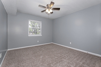 spacious bedroom with overhead light and fan