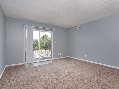 an empty living room with a door to a balcony