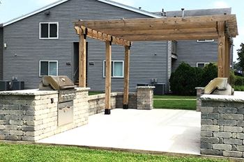a patio with a pergola and barbecue grilling area