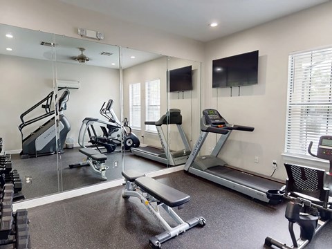A spacious gym with treadmills, elliptical machines, and a television.