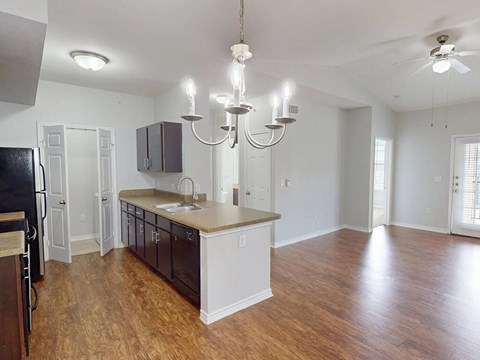 A kitchen with a black refrigerator and wooden floors.