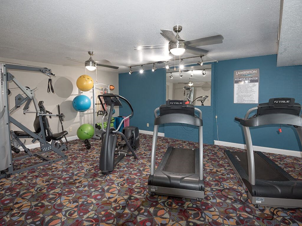 a gym with exercise equipment and a ceiling fan