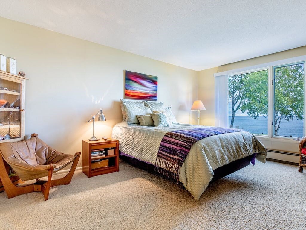 A bedroom with a bed, a chair, and a painting on the wall.