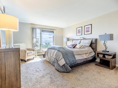 A bedroom with a large bed and a window overlooking the ocean.