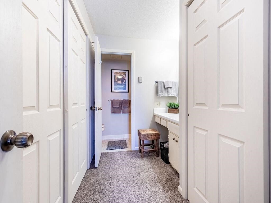 A hallway with white doors and a grey carpet.