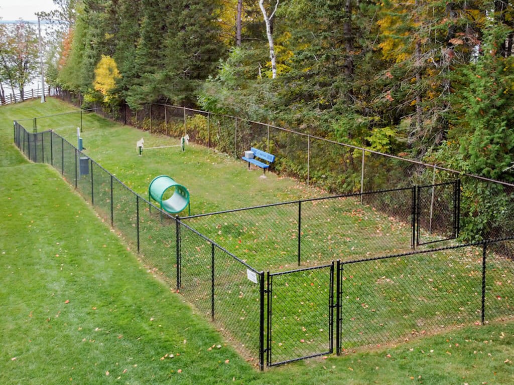 A black fence surrounds a green playground.