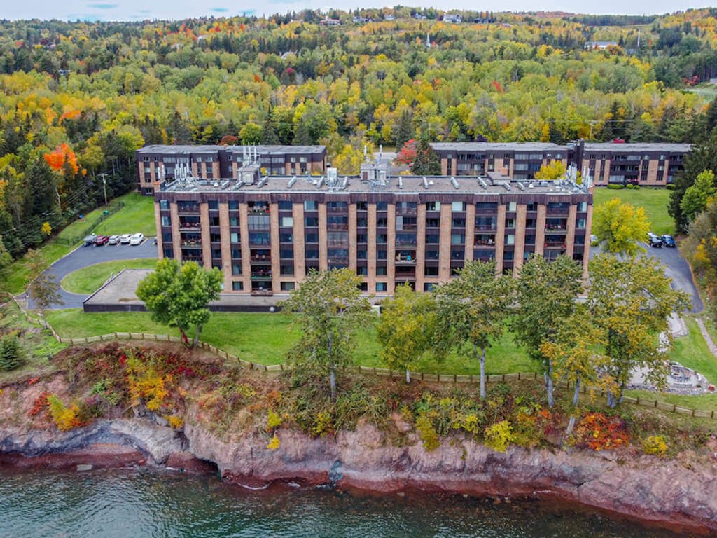 A large building sits on a cliff overlooking a body of water.